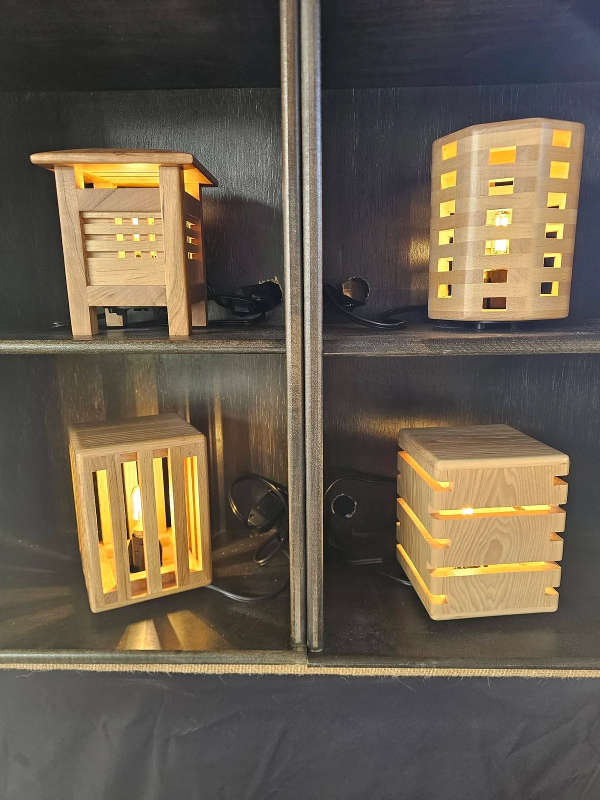 Four illuminated wooden nightlights in different slatted designs.
