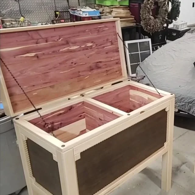 An open wooden hope chest with a divided interior, photographed in the workshop.